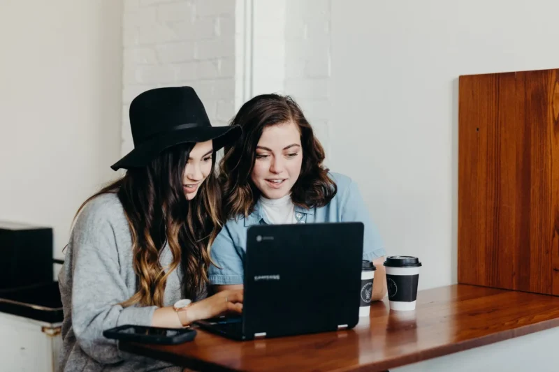 Two women using a small laptop.
