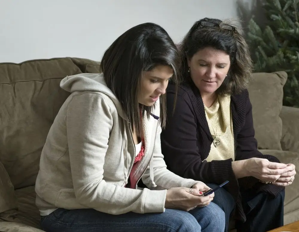 Mother and daughter reading messages on a smartphone.